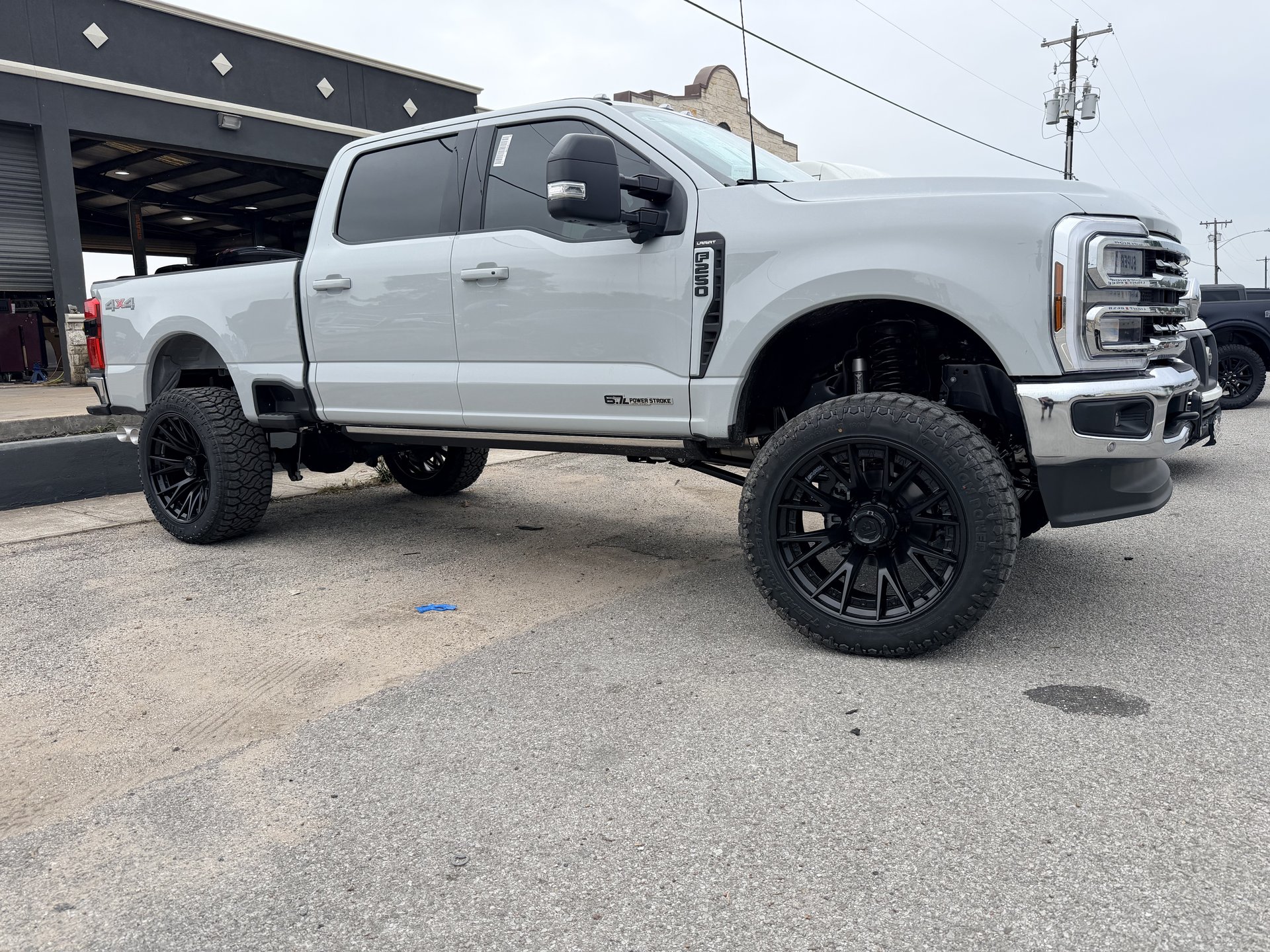 White Ford F-250 Lariat 6.7L Power Stroke with suspension lift and black custom wheels, Level Up Customs, Alvin TX